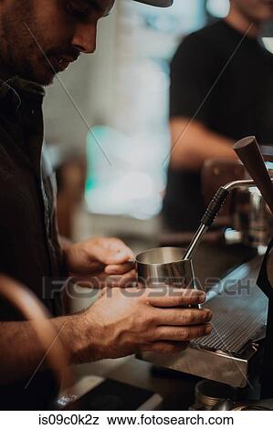 Barista heating milk jug on coffee machine in cafe, cropped shallow focus View Large Photo Image Stock Photo - Barista heating milk jug on coffee machine in cafe, cropped shallow focus. Fotosearch