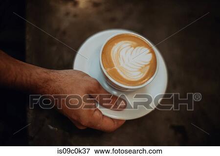 Barista placing cup of latte on cafe counter, overhead close up of hand View Large Photo Image Stock Photo - Barista placing cup of latte on cafe counter, overhead close up of hand. Fotosearch