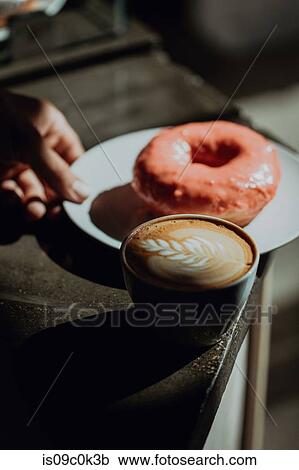 Barista placing ring doughnut by cup of latte on cafe counter, low key shallow focus View Large Photo Image Stock Image - Barista placing ring doughnut by cup of latte on cafe counter, low key shallow focus. Fotosearch