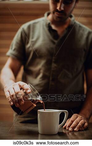 Barista pouring fresh black coffee into mug on cafe counter, shallow focus View Large Photo Image Stock Photograph - Barista pouring fresh black coffee into mug on cafe counter, shallow focus. Fotosearch