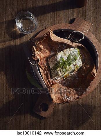 Stock Image - Barramundi baked in paperbark served in wooden bowl, a bush tucker dish using indigenous ingredients. Fotosearch