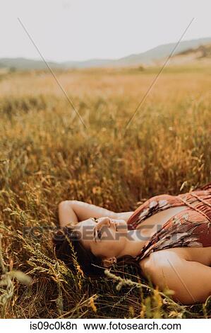 Beautiful young woman gazing up while lying in field of long grass, Exeter, California, USA View Large Photo Image Picture - Beautiful young woman gazing up while lying in field of long grass, Exeter, California, USA. Fotosearch