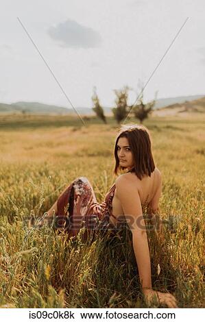 Beautiful young woman sitting in field of long grass looking over her shoulder, portrait, Exeter, California, USA View Large Photo Image Stock Image - Beautiful young woman sitting in field of long grass looking over her shoulder, portrait, Exeter, California, USA. Fotosearch