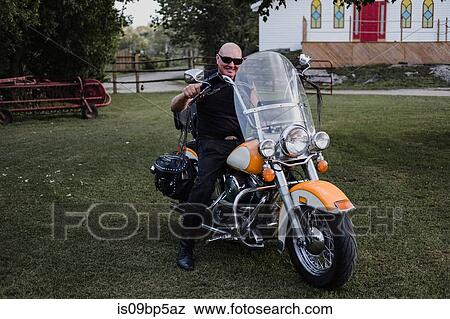 Stock Photo - Biker on his bike on lawn. Fotosearch