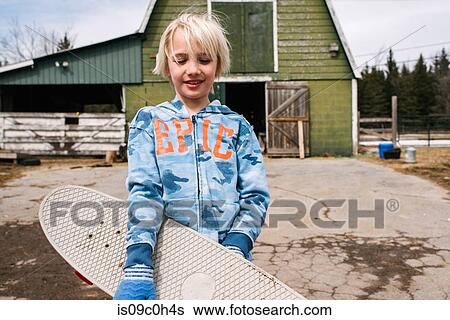 Blond boy carrying skateboard in farmyard, portrait View Large Photo Image Stock Photograph - Blond boy carrying skateboard in farmyard, portrait. Fotosearch