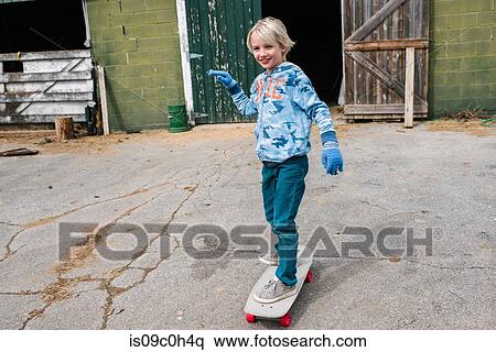 Blond boy skateboarding in farmyard View Large Photo Image Stock Photography - Blond boy skateboarding in farmyard. Fotosearch