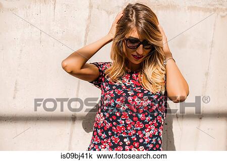Blond, stylish mid adult woman wearing sunglasses in front of wall with hands in hair View Large Photo Image Stock Image - Blond, stylish mid adult woman wearing sunglasses in front of wall with hands in hair. Fotosearch