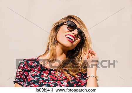 Blond, stylish mid adult woman wearing sunglasses in front of wall laughing View Large Photo Image Stock Image - Blond, stylish mid adult woman wearing sunglasses in front of wall laughing. Fotosearch