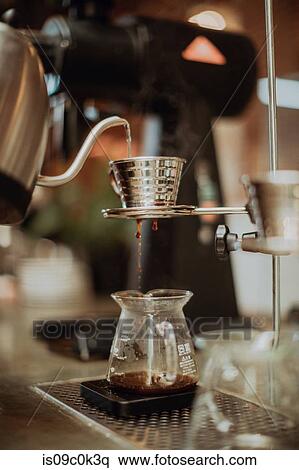 Boiled kettle water pouring into coffee filter and dripping into jug on cafe counter, shallow focus View Large Photo Image Stock Photography - Boiled kettle water pouring into coffee filter and dripping into jug on cafe counter, shallow focus. Fotosearch