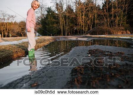 Boy ankle deep in rural puddle, portrait View Large Photo Image Stock Image - Boy ankle deep in rural puddle, portrait. Fotosearch