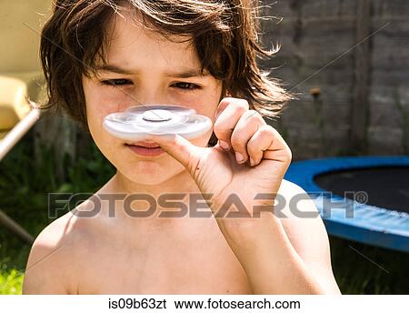 Boy balancing petal-shaped toy on thumb View Large Photo Image Stock Photograph - Boy balancing petal-shaped toy on thumb. Fotosearch