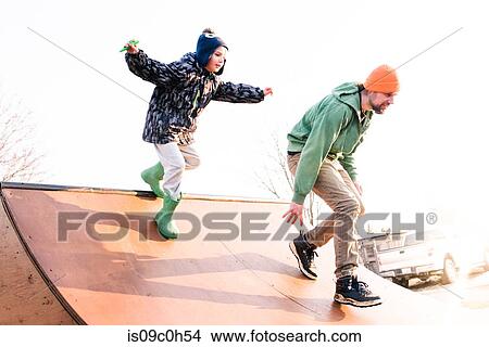 Boy chasing father on skateboard ramp, low angle view View Large Photo Image Picture - Boy chasing father on skateboard ramp, low angle view. Fotosearch