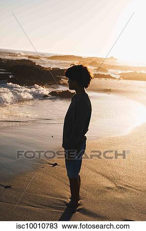Boy daydreaming on beach at sunset View Large Photo Image Stock Image - Boy daydreaming on beach at sunset. Fotosearch