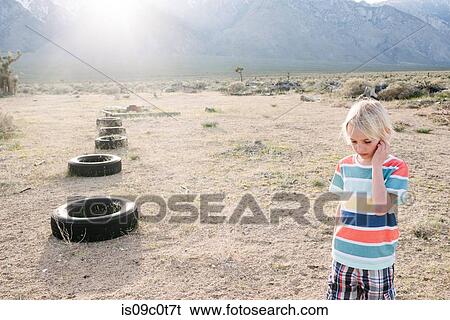 Boy exploring beside row of tyres, Olancha, California, US View Large Photo Image Stock Photograph - Boy exploring beside row of tyres, Olancha, California, US. Fotosearch