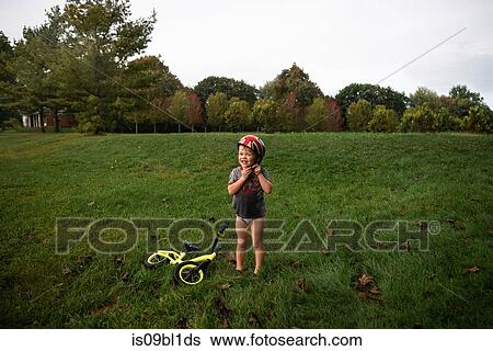Boy fastening helmet in park View Large Photo Image Stock Photograph - Boy fastening helmet in park. Fotosearch