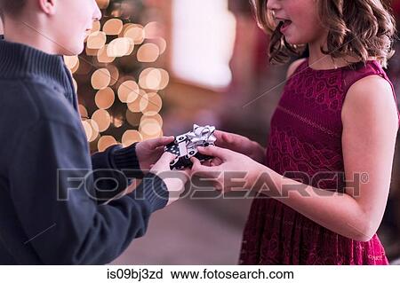 Boy handing over Christmas gift to girl View Large Photo Image Stock Image - Boy handing over Christmas gift to girl. Fotosearch