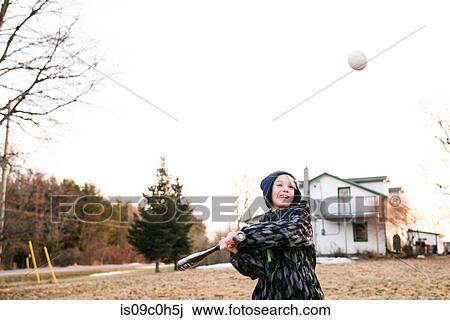 Boy hitting baseball ball in rural field, action View Large Photo Image Stock Image - Boy hitting baseball ball in rural field, action. Fotosearch