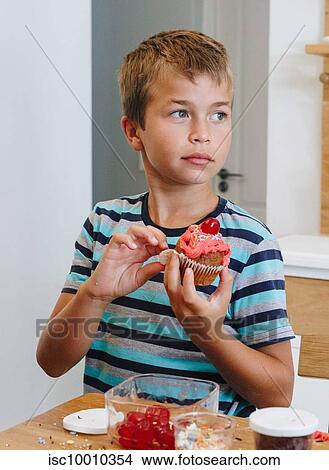 Boy holding cupcake at home View Large Photo Image Picture - Boy holding cupcake at home. Fotosearch