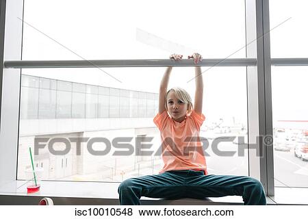 Boy holding handrail in airport window seat, three quarter length portrait View Large Photo Image Stock Photo - Boy holding handrail in airport window seat, three quarter length portrait. Fotosearch