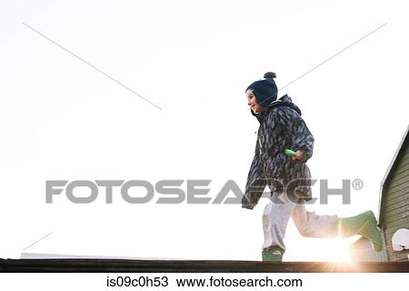Boy in knit hat running across sunlit skateboard ramp, low angle view View Large Photo Image Stock Image - Boy in knit hat running across sunlit skateboard ramp, low angle view. Fotosearch