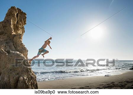 Boy jumping off rock, El Matador Beach, Malibu, USA View Large Photo Image Stock Image - Boy jumping off rock, El Matador Beach, Malibu, USA. Fotosearch
