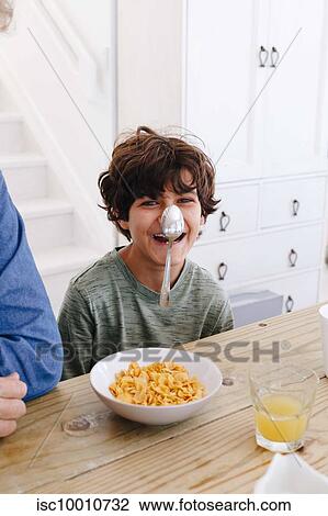 Boy laughing at spoon sticking on nose at breakfast View Large Photo Image Stock Image - Boy laughing at spoon sticking on nose at breakfast. Fotosearch