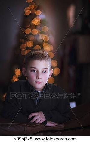 Boy leaning over sofa, Christmas tree in background View Large Photo Image Stock Photo - Boy leaning over sofa, Christmas tree in background. Fotosearch