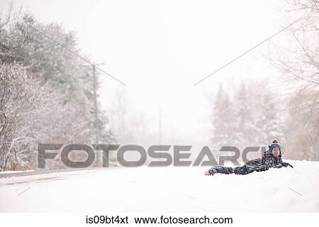 Boy lying on snow in winter landscape View Large Photo Image Stock Photograph - Boy lying on snow in winter landscape. Fotosearch