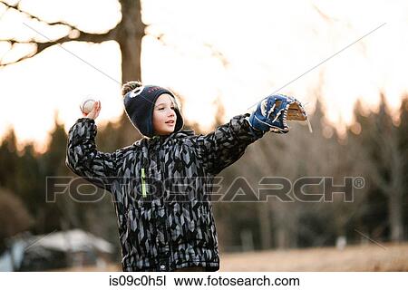 Stock Image - Boy preparing to throw baseball ball in rural field. Fotosearch