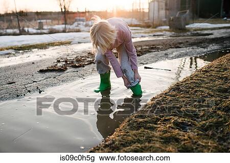 Boy rolling trousers up in rural meltwater puddle View Large Photo Image Stock Image - Boy rolling trousers up in rural meltwater puddle. Fotosearch