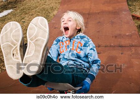 Boy sitting and skateboarding backwards down wooden skateboard ramp View Large Photo Image Picture - Boy sitting and skateboarding backwards down wooden skateboard ramp. Fotosearch