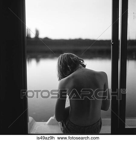 Boy sitting on edge of barge, rear view View Large Photo Image Stock Image - Boy sitting on edge of barge, rear view. Fotosearch