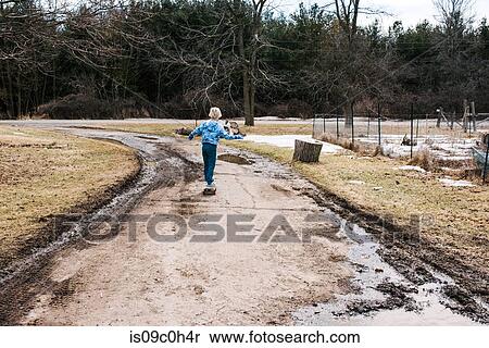 Stock Photography - Boy skateboarding along dirt track, rear view. Fotosearch