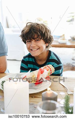Stock Image - Boy smiling at dining table in home party. Fotosearch