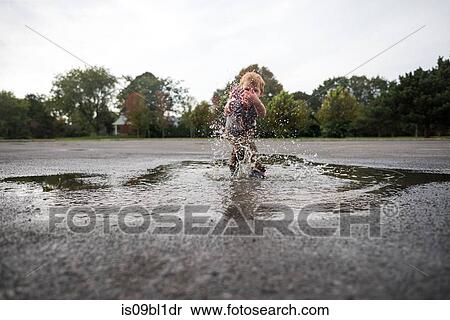 Boy splashing in puddle on road View Large Photo Image Stock Photography - Boy splashing in puddle on road. Fotosearch