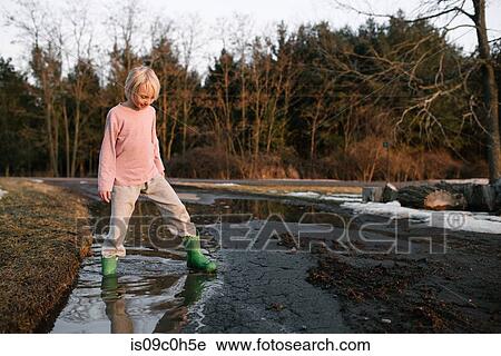 Boy stepping ankle deep in rural meltwater puddle View Large Photo Image Stock Image - Boy stepping ankle deep in rural meltwater puddle. Fotosearch