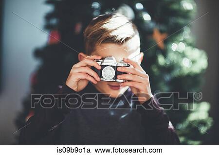 Boy taking photo, Christmas tree in background View Large Photo Image Stock Image - Boy taking photo, Christmas tree in background. Fotosearch