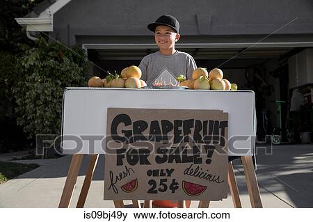 Stock Photo - Boy with homemade grapefruit stall on driveway. Fotosearch