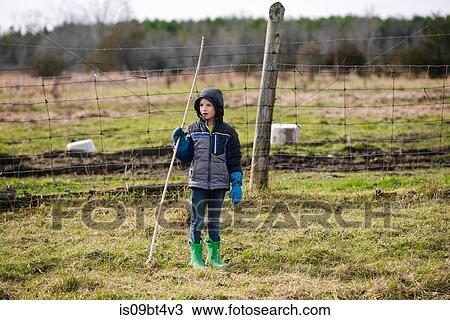Boy with stick exploring field View Large Photo Image Stock Image - Boy with stick exploring field. Fotosearch