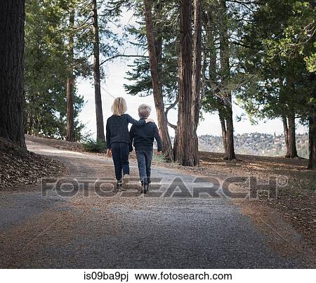 Stock Image - Boys walking on road through woods, Lake Arrowhead, California, USA. Fotosearch