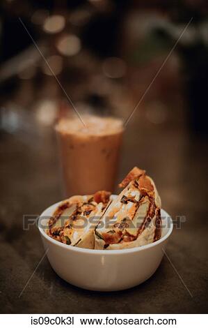 Stock Image - Breakfast wraps and glass of iced coffee on cafe table, shallow focus close up. Fotosearch