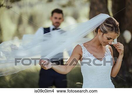 Bride and groom holding delicate wedding veil in woodland View Large Photo Image Picture - Bride and groom holding delicate wedding veil in woodland. Fotosearch