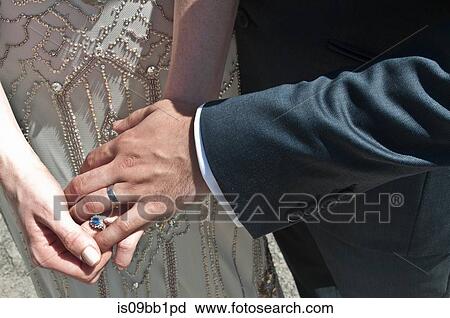 Stock Image - Bride and groom, holding hands, close-up, mid section. Fotosearch