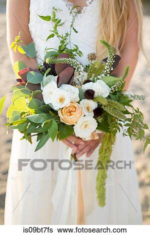 Stock Photograph - Bride with bouquet on beach. Fotosearch