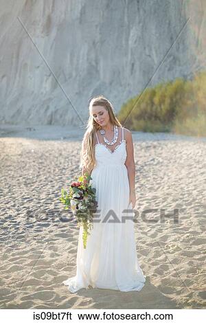 Stock Photograph - Bride with bouquet on beach. Fotosearch