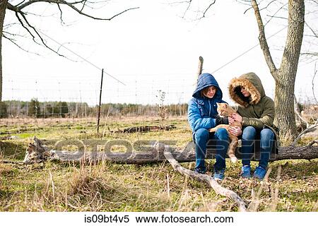 Stock Photography - Brother and sister cuddling cat in field. Fotosearch