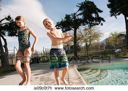 Stock Image - Brother and sister playing by swimming pool, Olancha, California, US. Fotosearch
