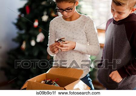 Stock Image - Brother and sister putting up Christmas decorations. Fotosearch