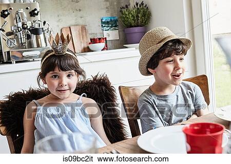 Stock Photograph - Brother and sister sitting at dinner table, smiling. Fotosearch