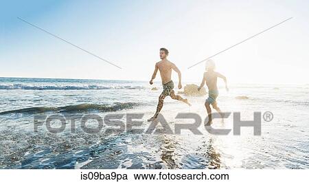 Stock Image - Brothers running on El Matador Beach, Malibu, USA. Fotosearch